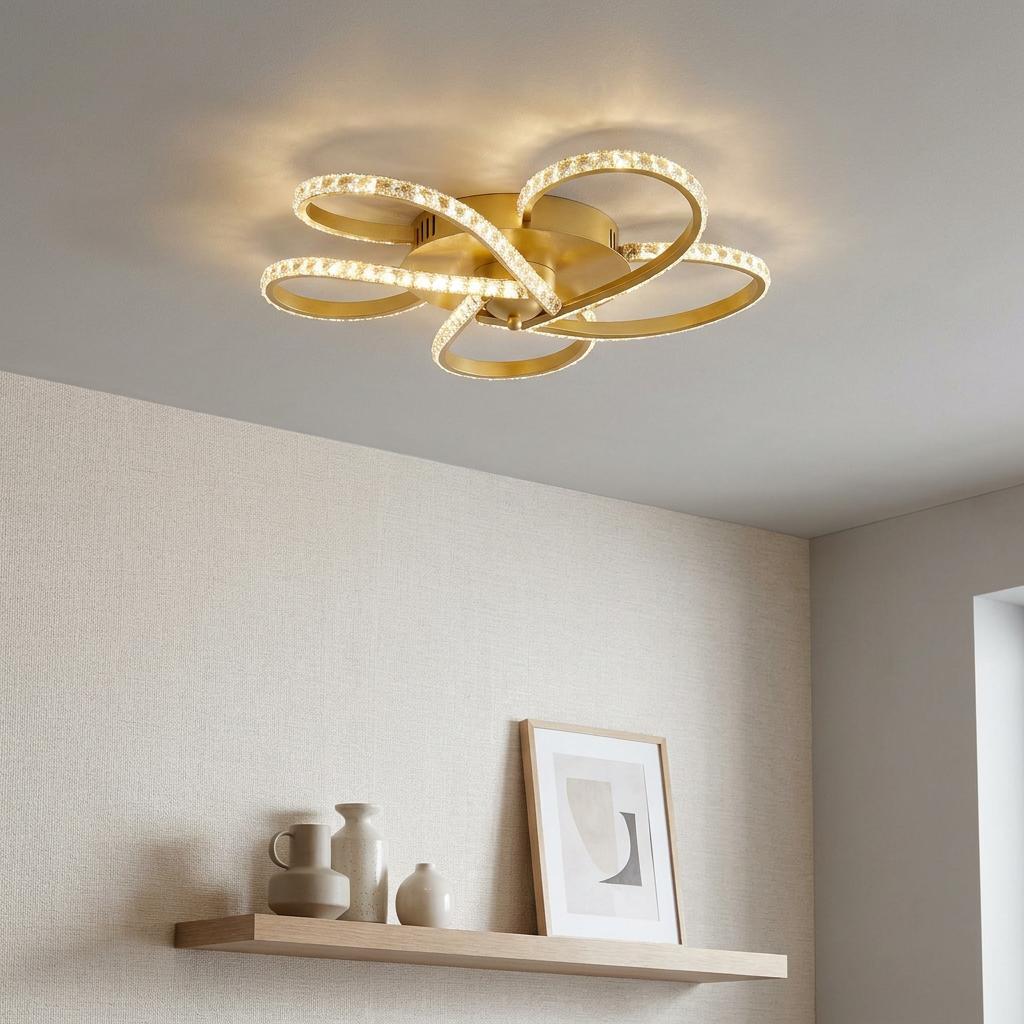 A flower-shaped gold LED flush ceiling light with crystal-studded loops illuminating a modern room.