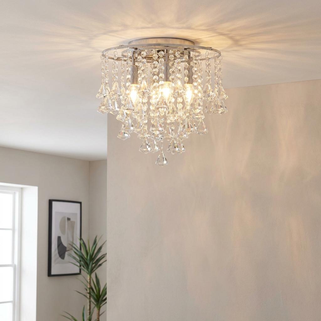 A chrome and crystal flush ceiling light illuminating a living room with warm, patterned shadows.