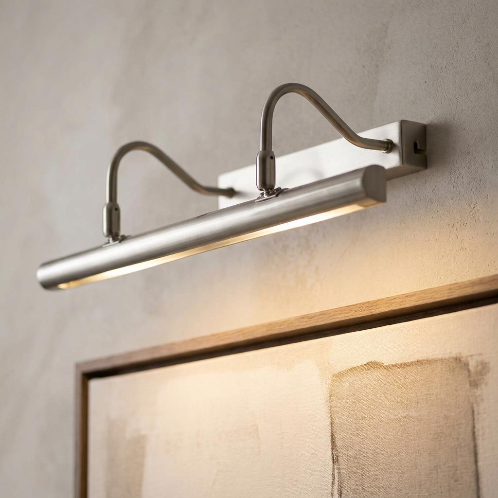 Double-arm antique chrome picture light mounted on a textured wall illuminating framed artwork.