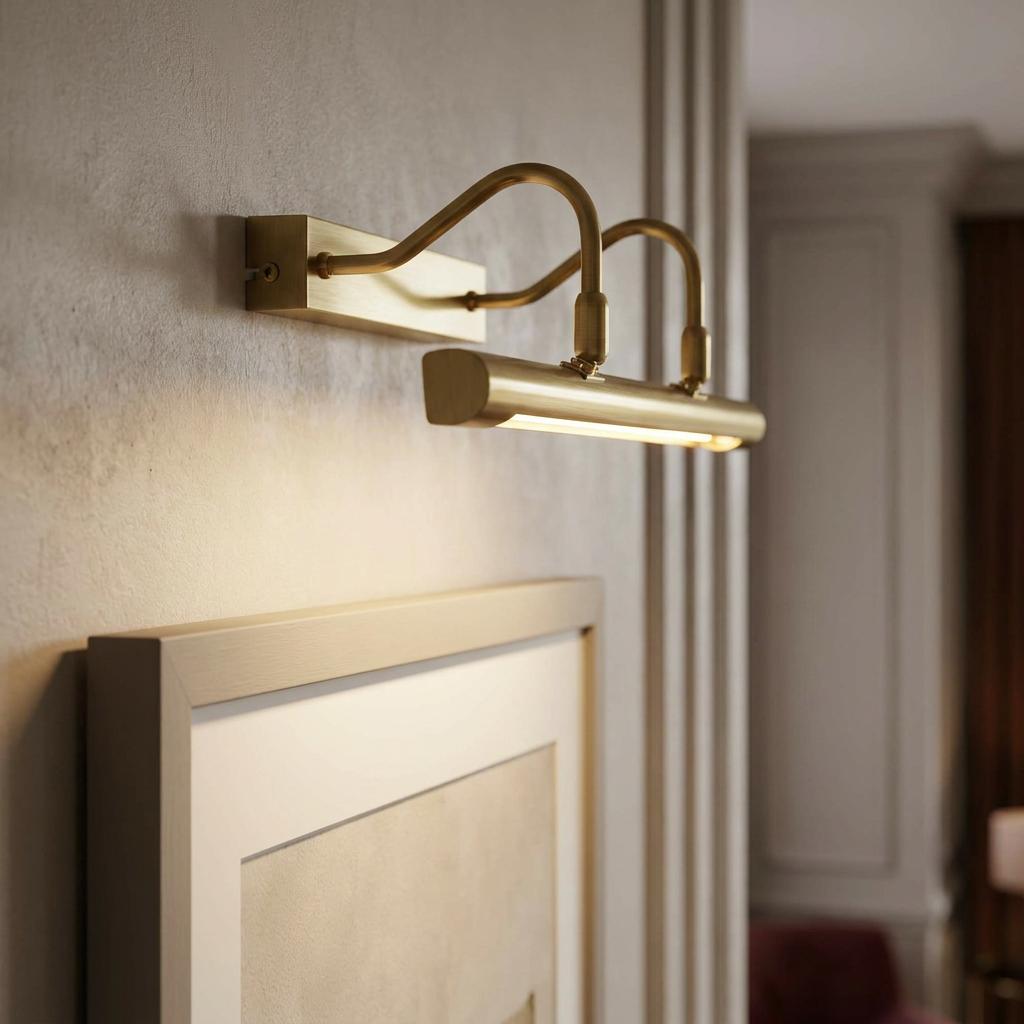 Double arm satin brass picture light casting a warm glow over a framed picture on a textured wall.
