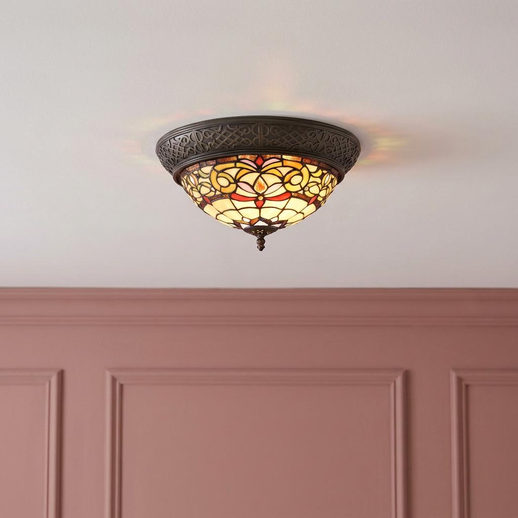 Durham flush Tiffany ceiling light with warm stained glass patterns mounted on a white ceiling above pink paneling.