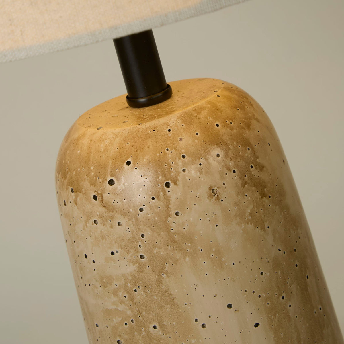 Close-up of the Agra lamp's pitted travertine-effect stone base and black fitting