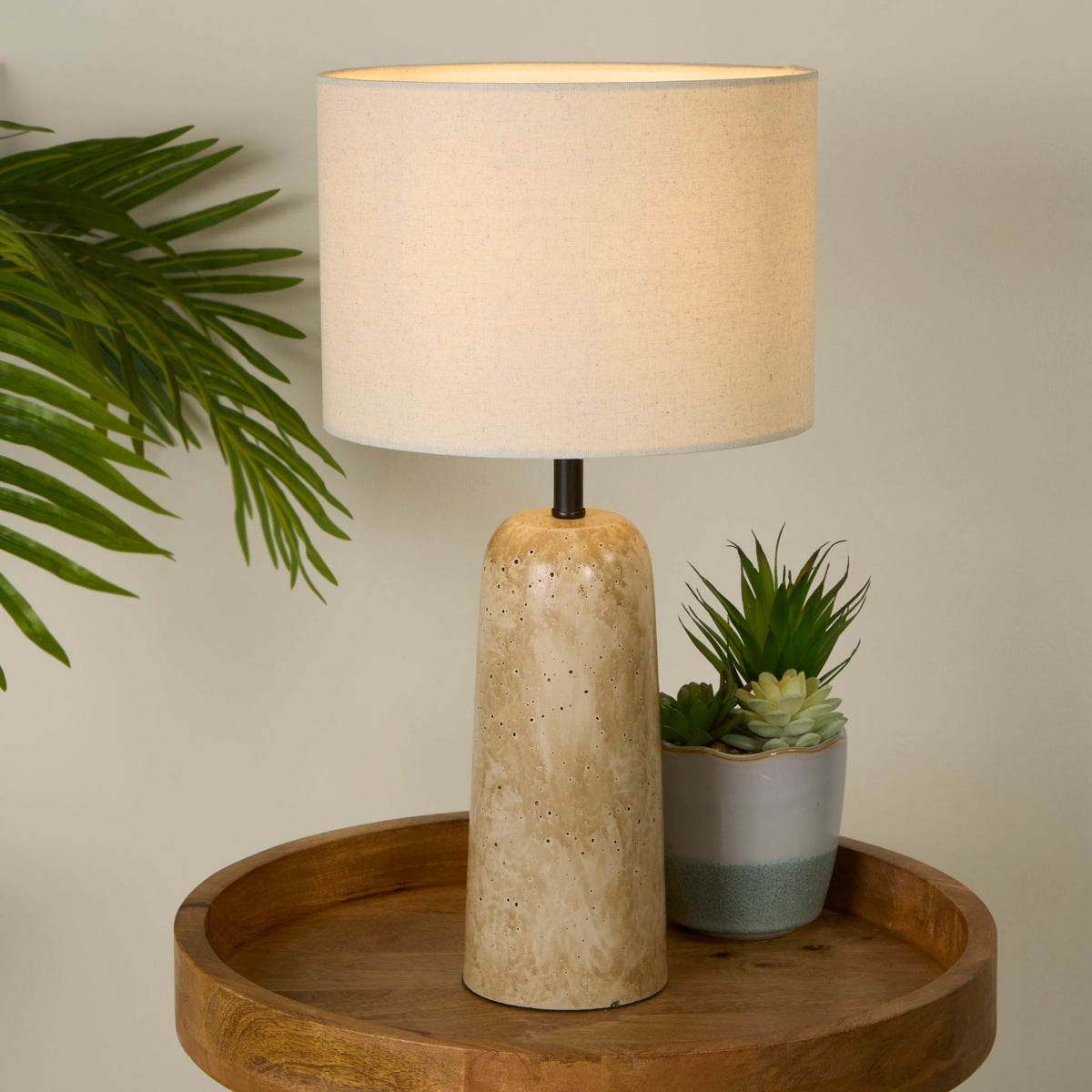 Agra lamp lit on a wooden tray beside potted succulents in a calm neutral living space