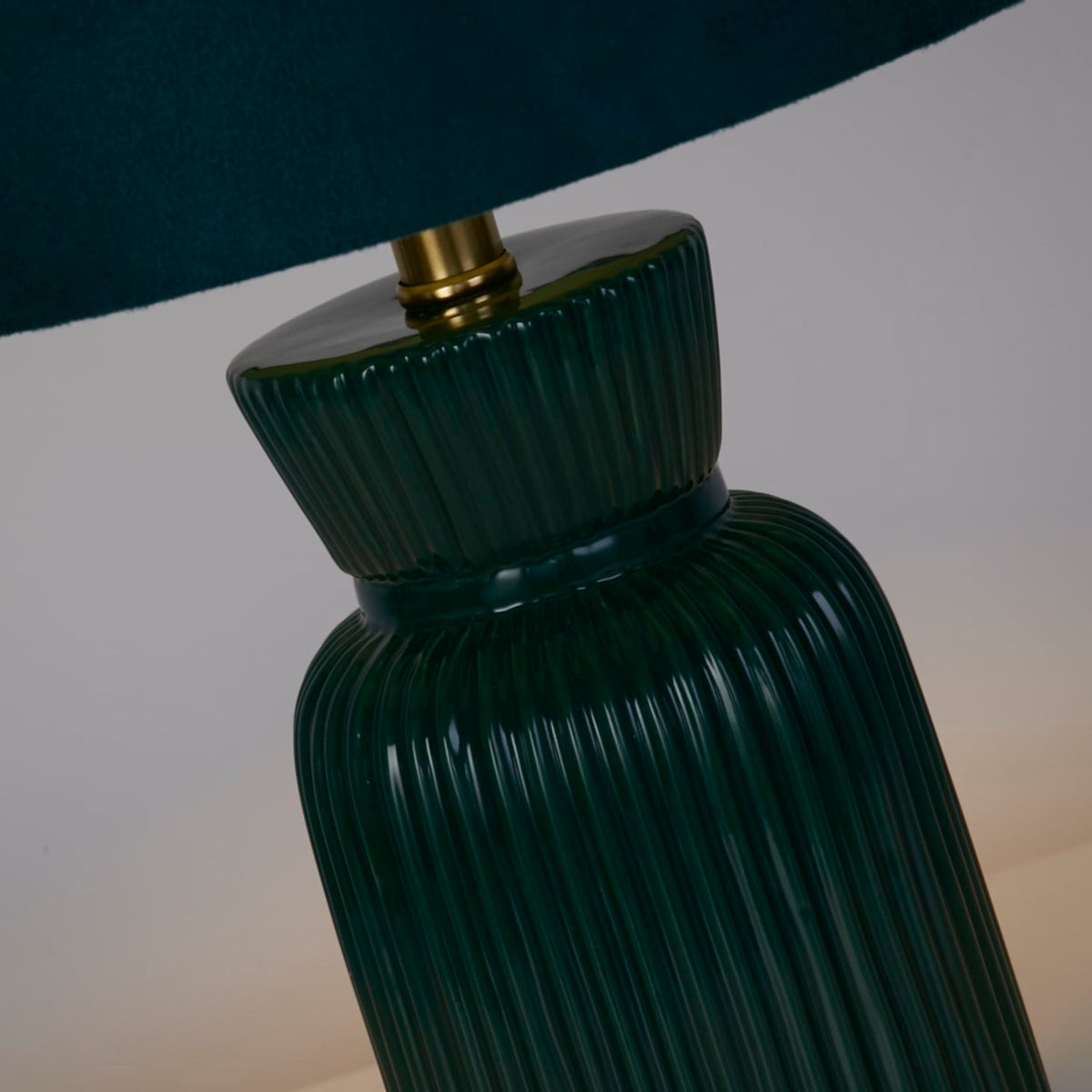 Close-up of Tia lamp's glossy ribbed emerald ceramic base and brass lampholder