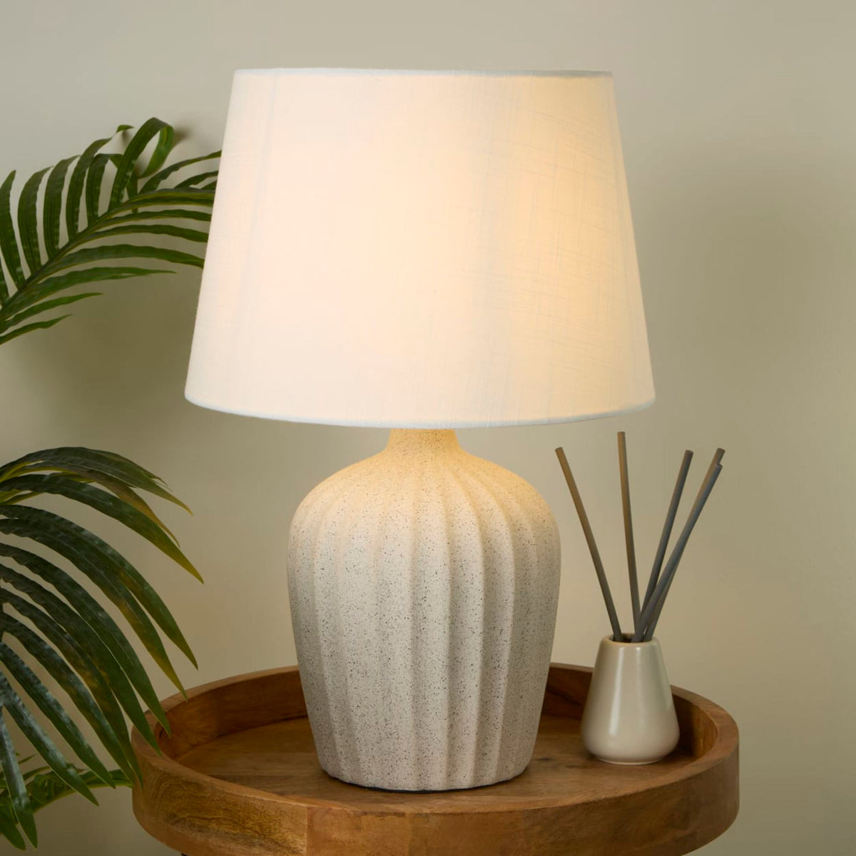 Padstow terrazzo lamp on a round wooden table with a reed diffuser and palm leaves