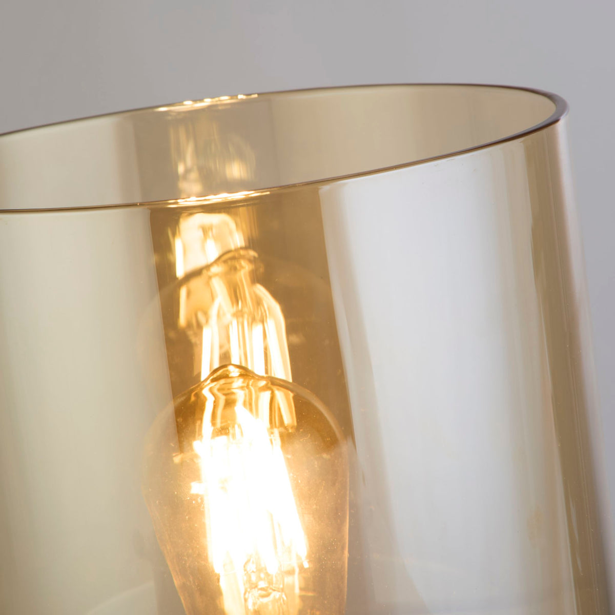 Close-up of the Sweden lamp's amber glass rim and warm vintage filament bulb