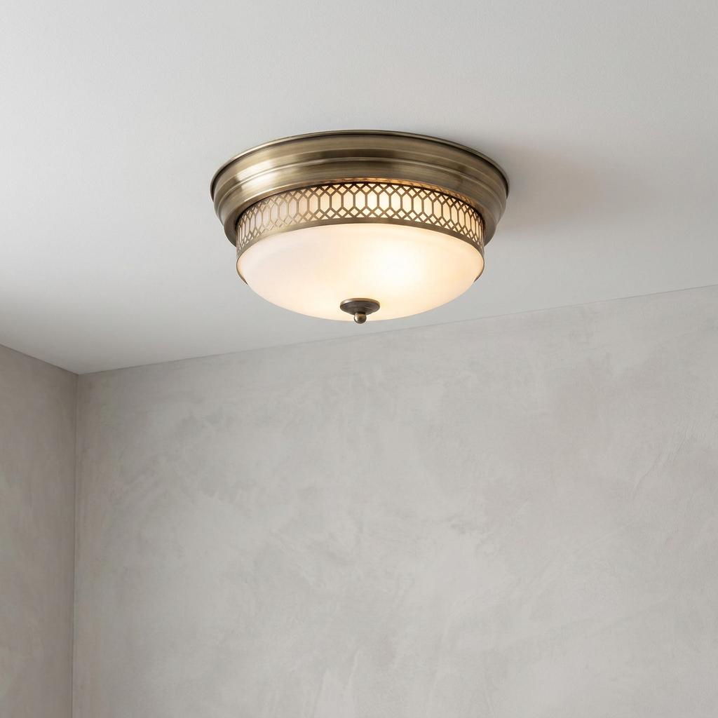 Brass flush mount light with opal glass shade and decorative fretwork trim mounted on a white ceiling.