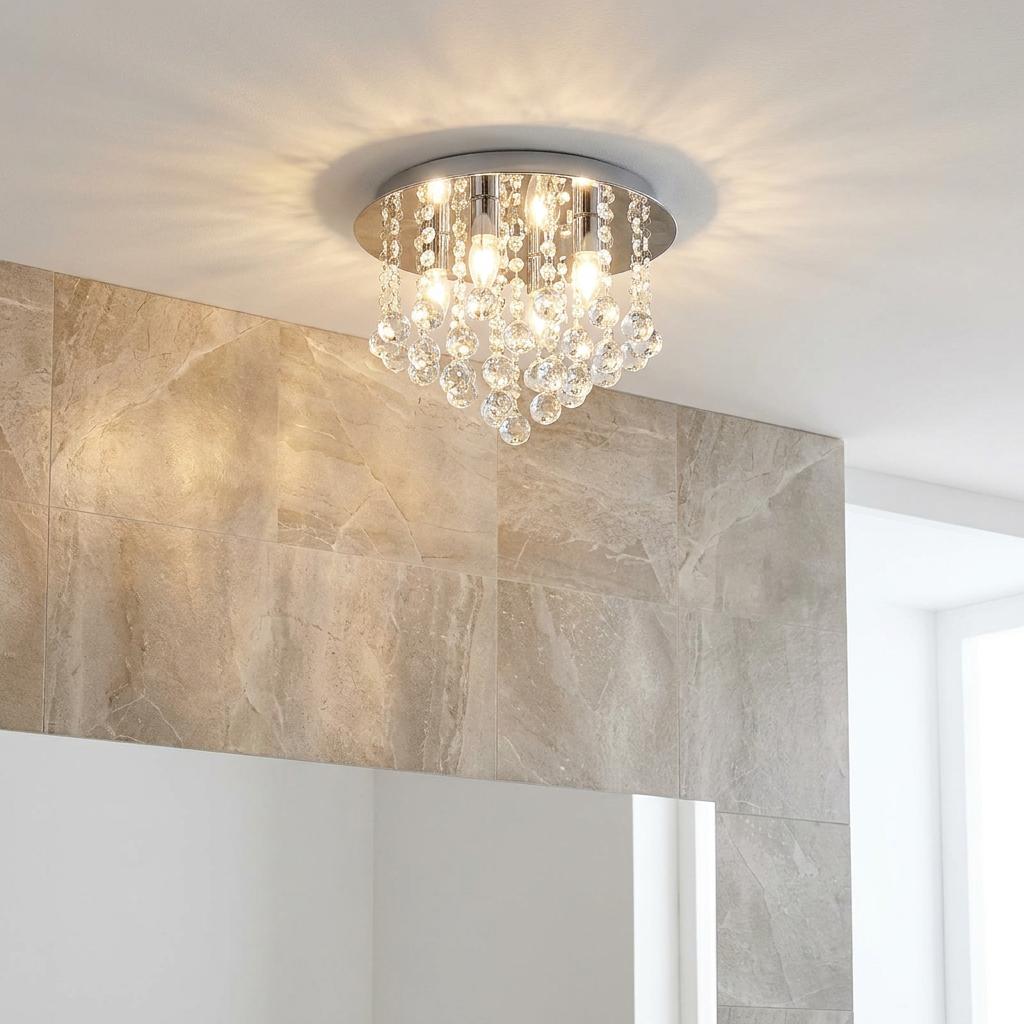 Chrome flush ceiling light with cascading crystal spheres illuminating a modern tiled bathroom interior.
