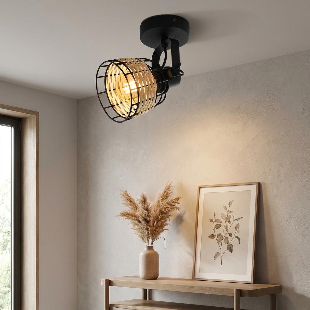 Black and rattan ceiling spotlight illuminating a minimalist room with a wooden console table and botanical art.