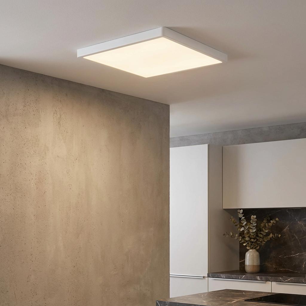 A square white LED flush ceiling light illuminates a modern kitchen with neutral-toned walls.