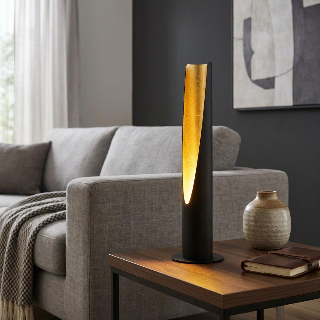 Eglo Barbotto tube-shaped black and gold LED table lamp on a wooden table beside a grey sofa.