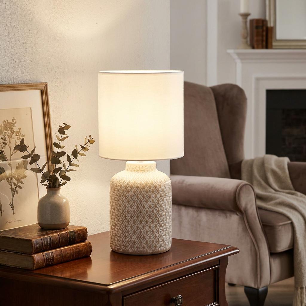 Eglo Bellariva table lamp with a patterned ceramic base and white fabric shade glowing on a dark wood side table.