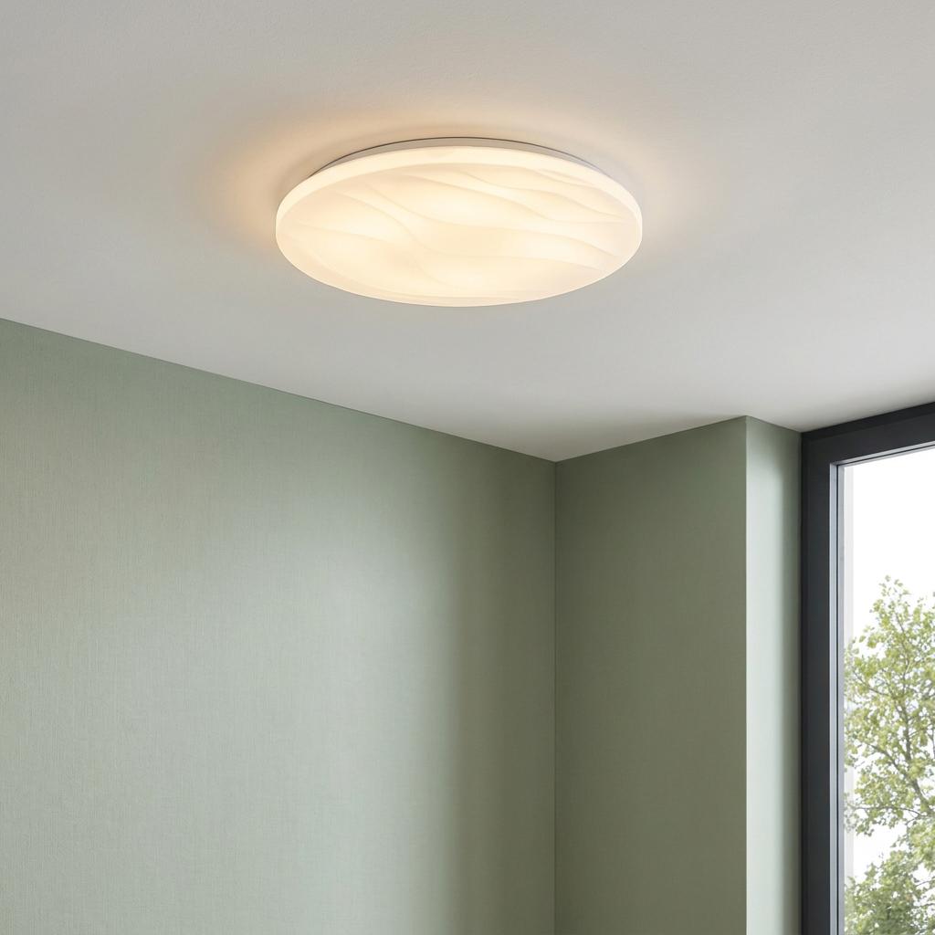 Round white LED flush ceiling light with a wavy textured shade glowing in a room with green walls.