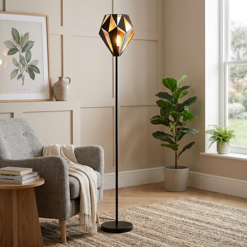 Modern black and copper geometric floor lamp in a stylish living room beside a grey armchair and fiddle-leaf fig.