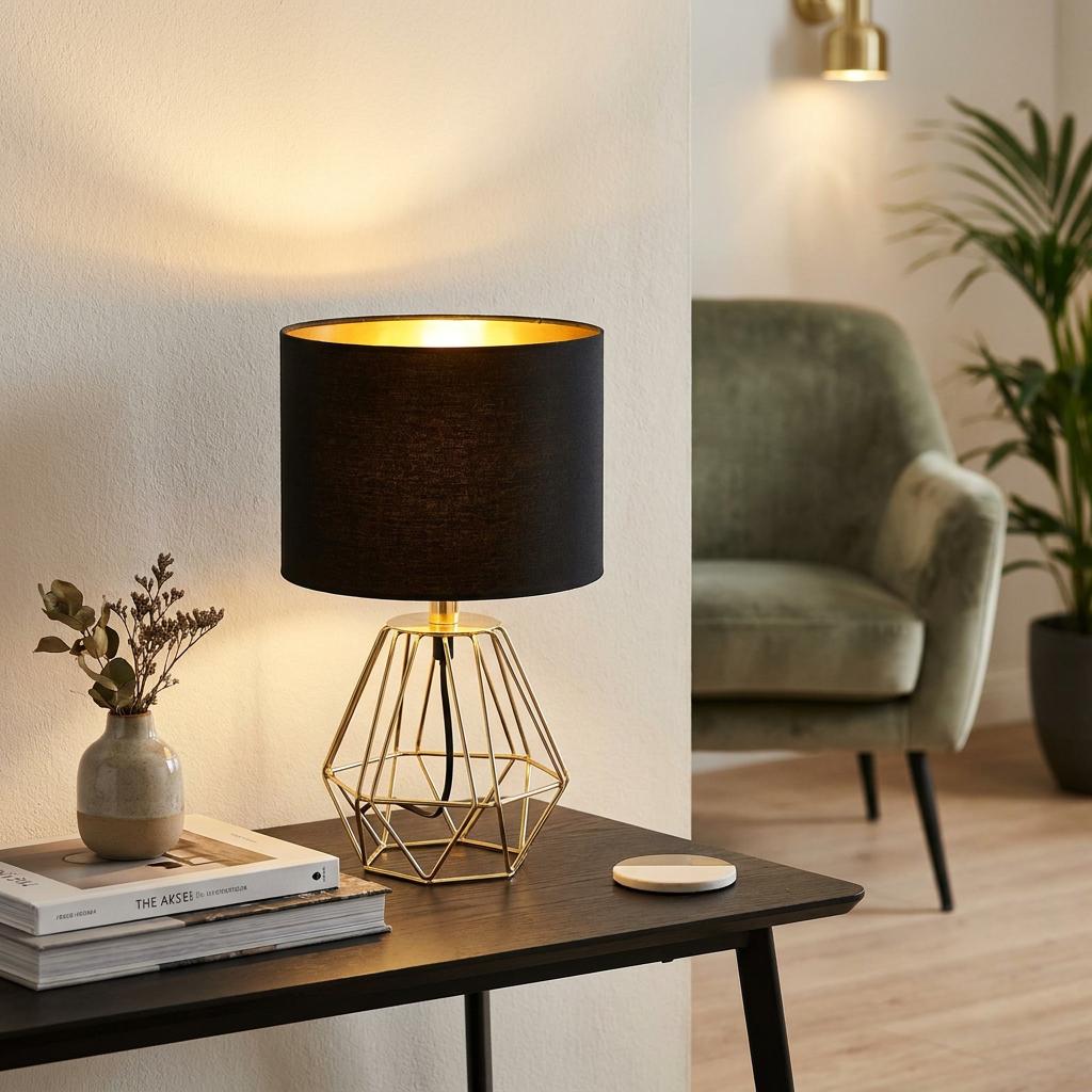 Eglo Carlton 2 table lamp with a gold geometric base and black shade, lit on a dark wood table in a modern room.