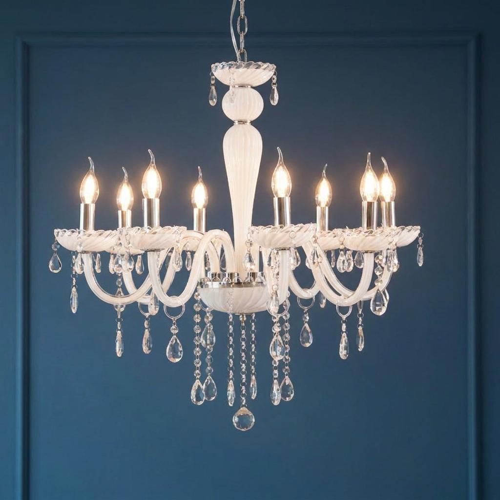 Eight-light white glass chandelier with crystal droplets glowing against a dark blue wall.