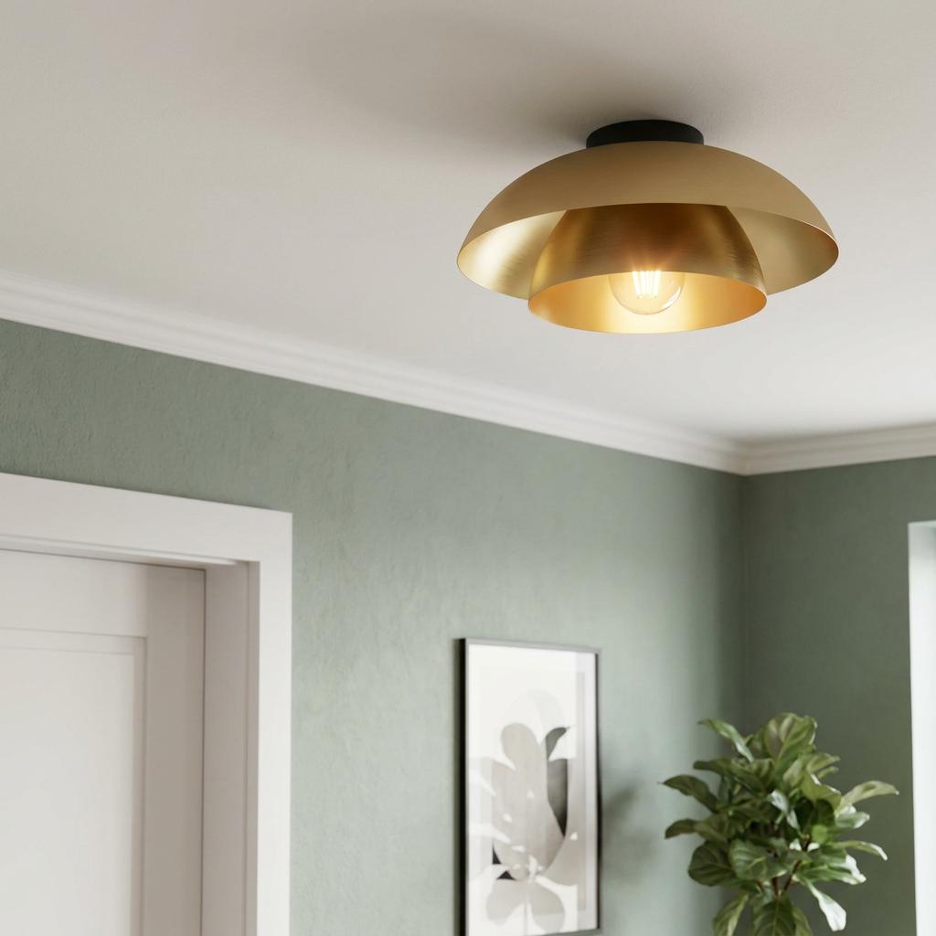 Gold double-dome flush ceiling light illuminated in a room with sage green walls and white molding.