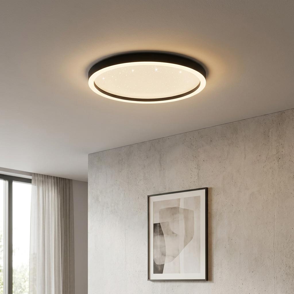 A round black flush-mount ceiling light with a starry effect diffuser illuminated in a modern interior.