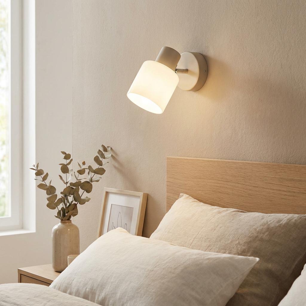 Sand-colored wall spotlight with a white glass shade illuminated above a wooden headboard.