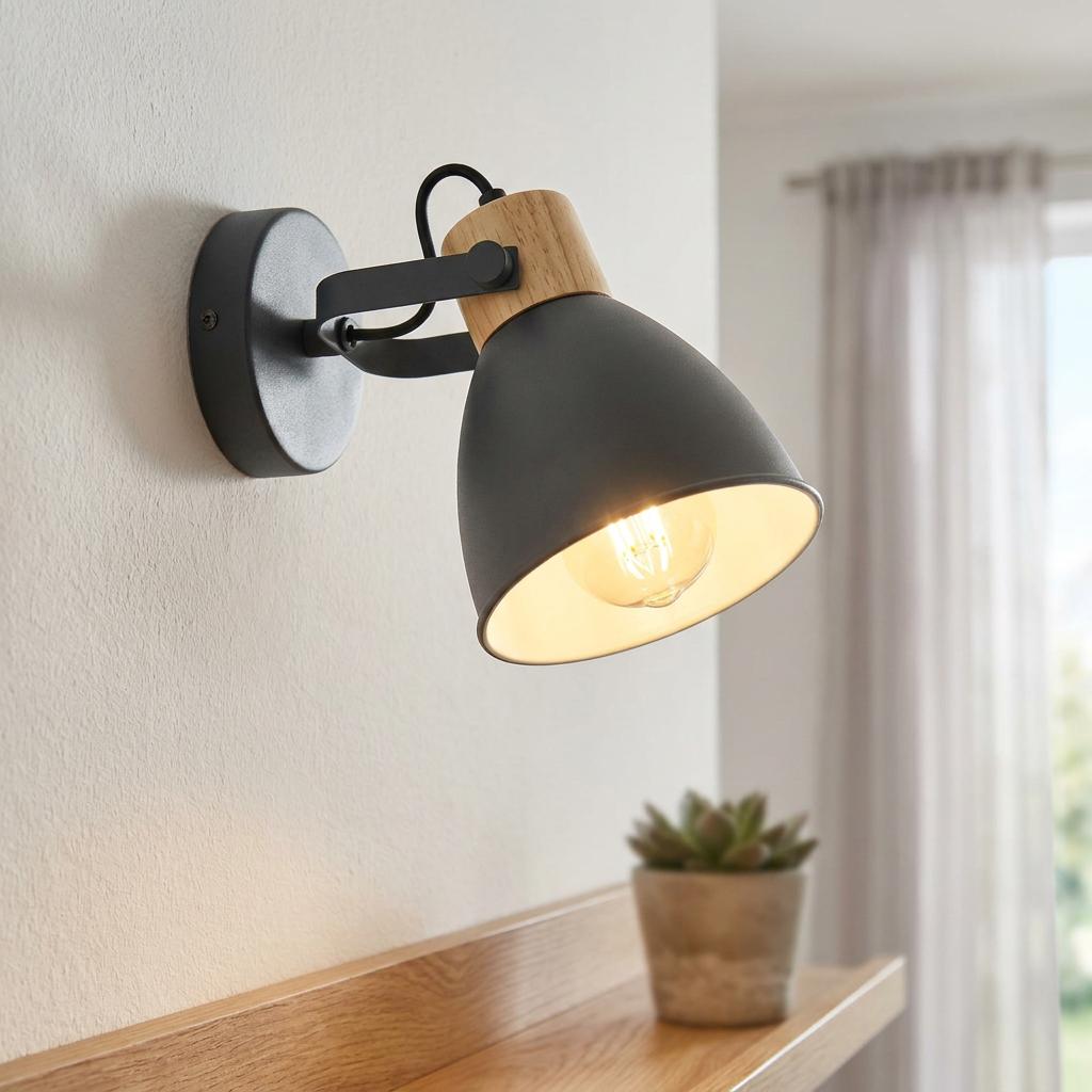 Matte grey and natural wood wall-mounted spotlight with a warm glowing bulb on a white wall.