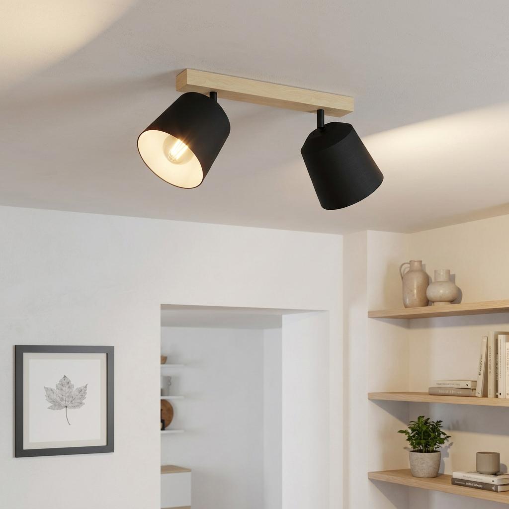 Two adjustable black spotlights on a light wood bar mounted to a white ceiling in a modern room.