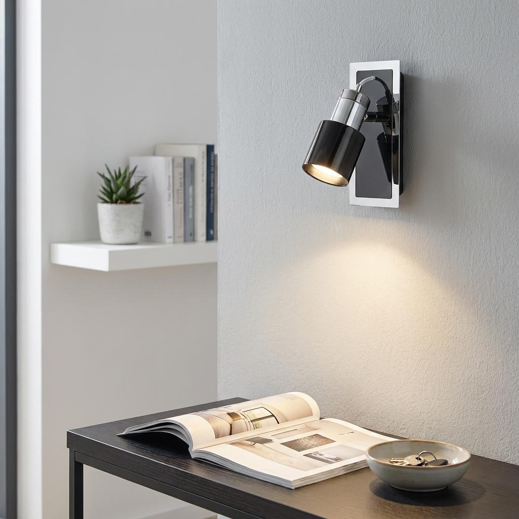 Eglo Davida 1 black nickel and chrome wall spotlight illuminating an open book on a dark desk.
