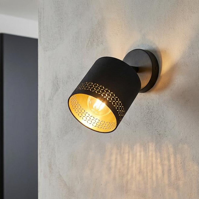 A modern black and gold wall spotlight illuminating a kitchen wall above cookbooks and a bowl of lemons.