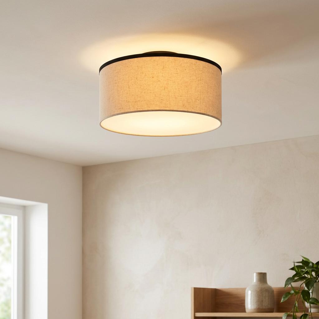 Natural linen drum shade flush ceiling light with a dark trim, glowing warmly in a modern interior setting.