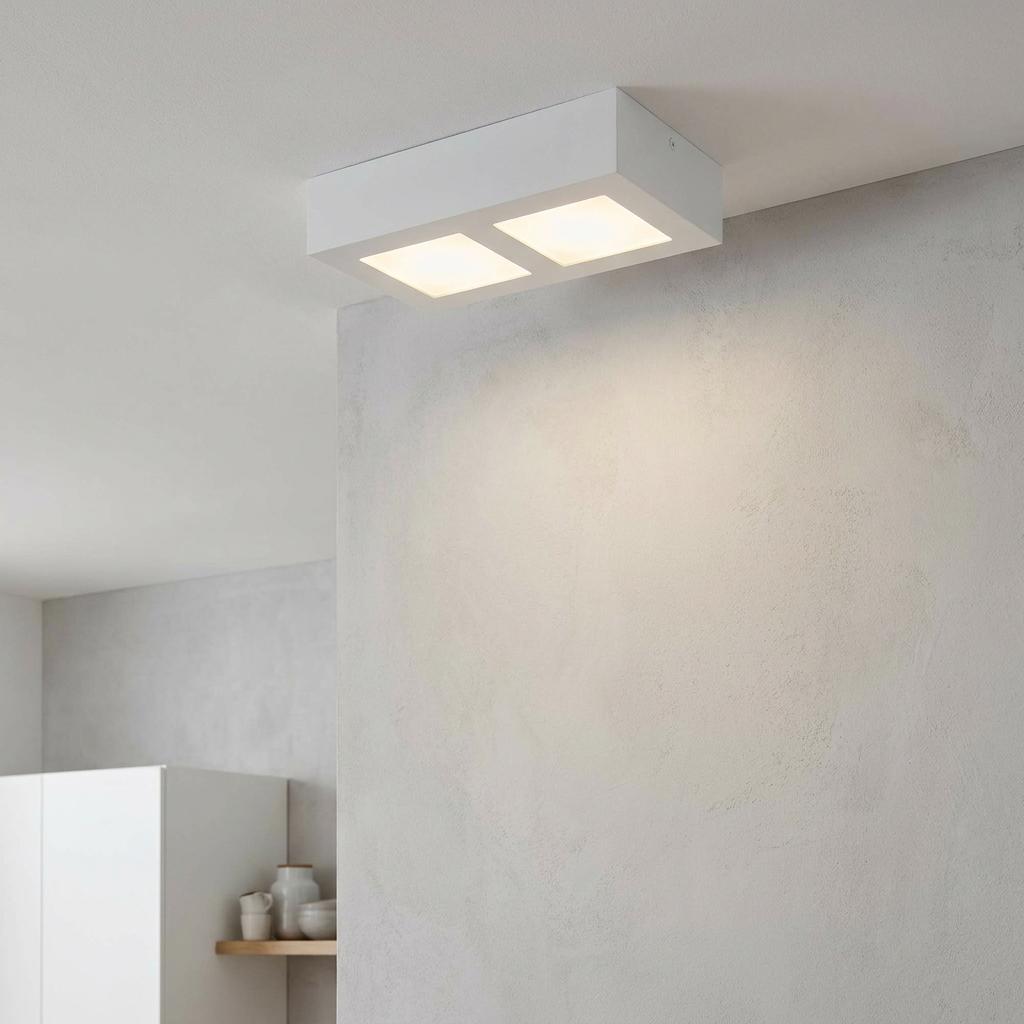Rectangular white flush mount ceiling light with two glowing square panels illuminating a textured grey wall.