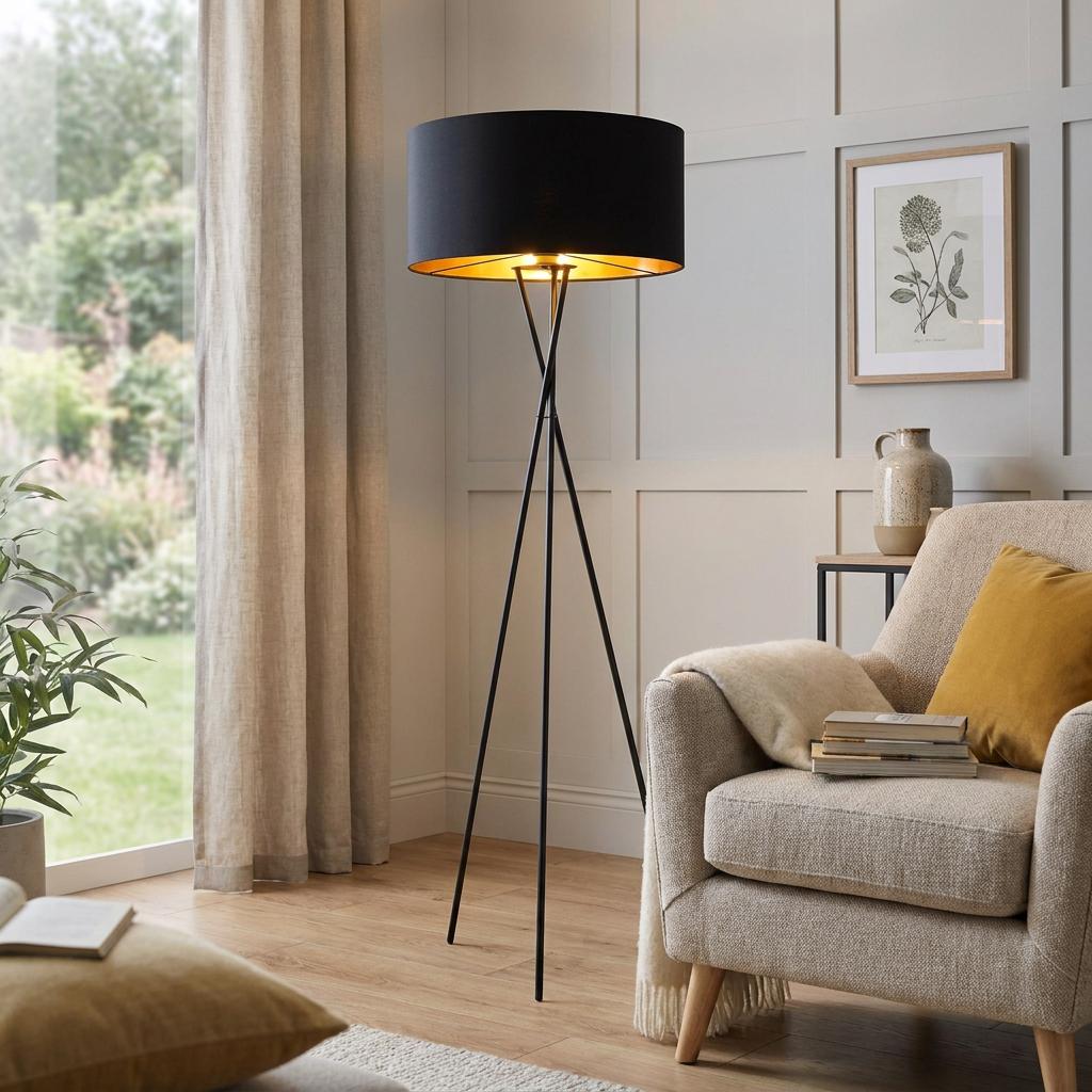 Black tripod floor lamp with a copper interior shade, standing beside a cream armchair in a living room.