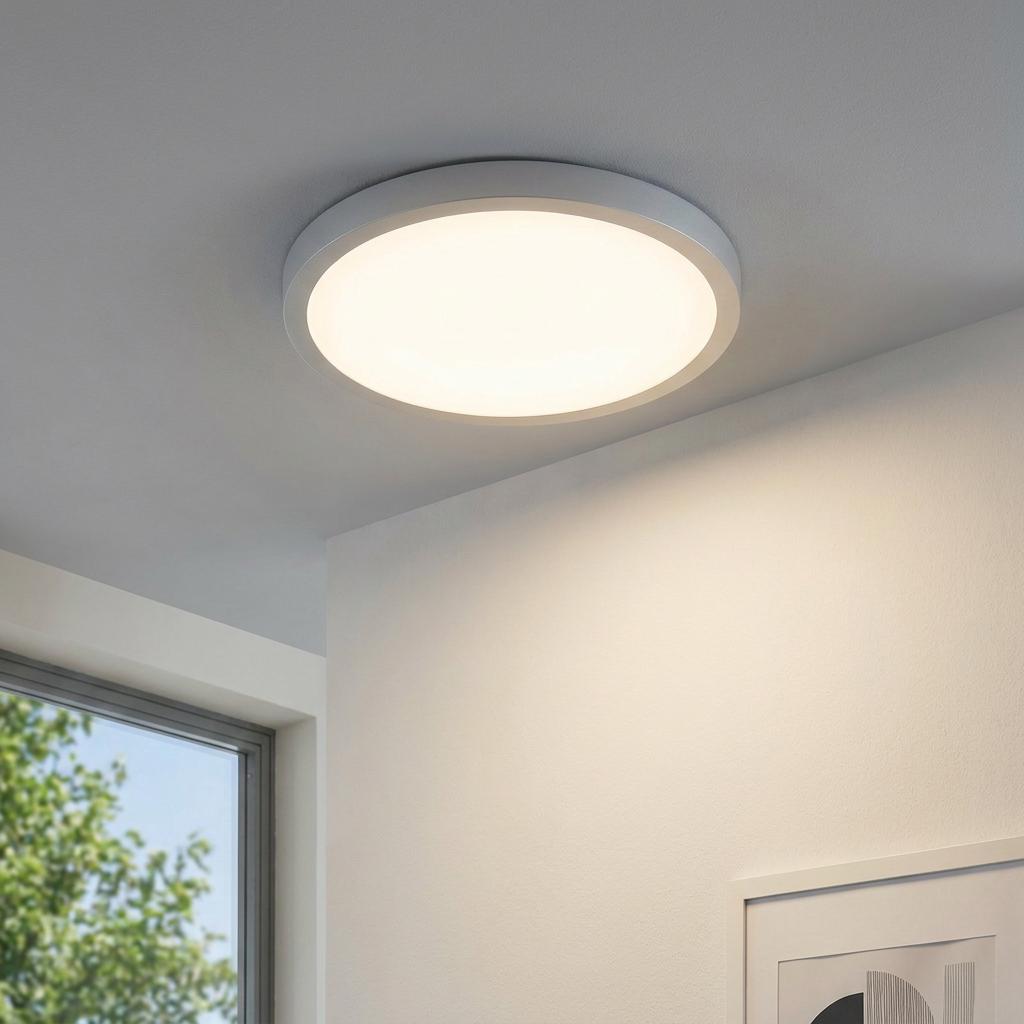 Eglo Fueva 1 LED round silver flush ceiling light illuminated on a white ceiling in a modern room.