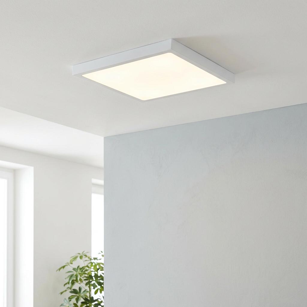 Square white flush LED ceiling light illuminated in a minimalist modern interior.
