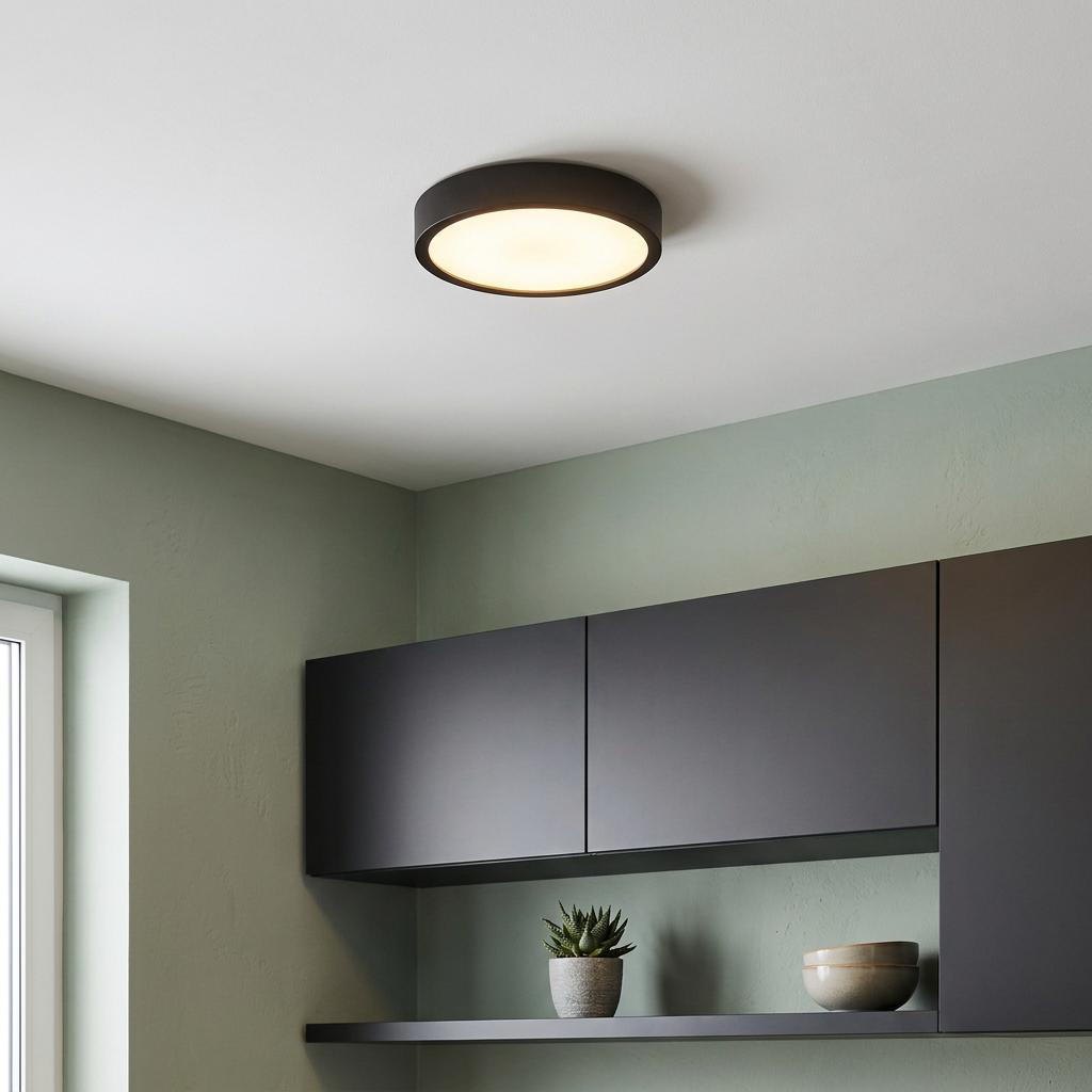 A round black flush-mount LED ceiling light illuminates a modern kitchen with grey cabinets and green walls.