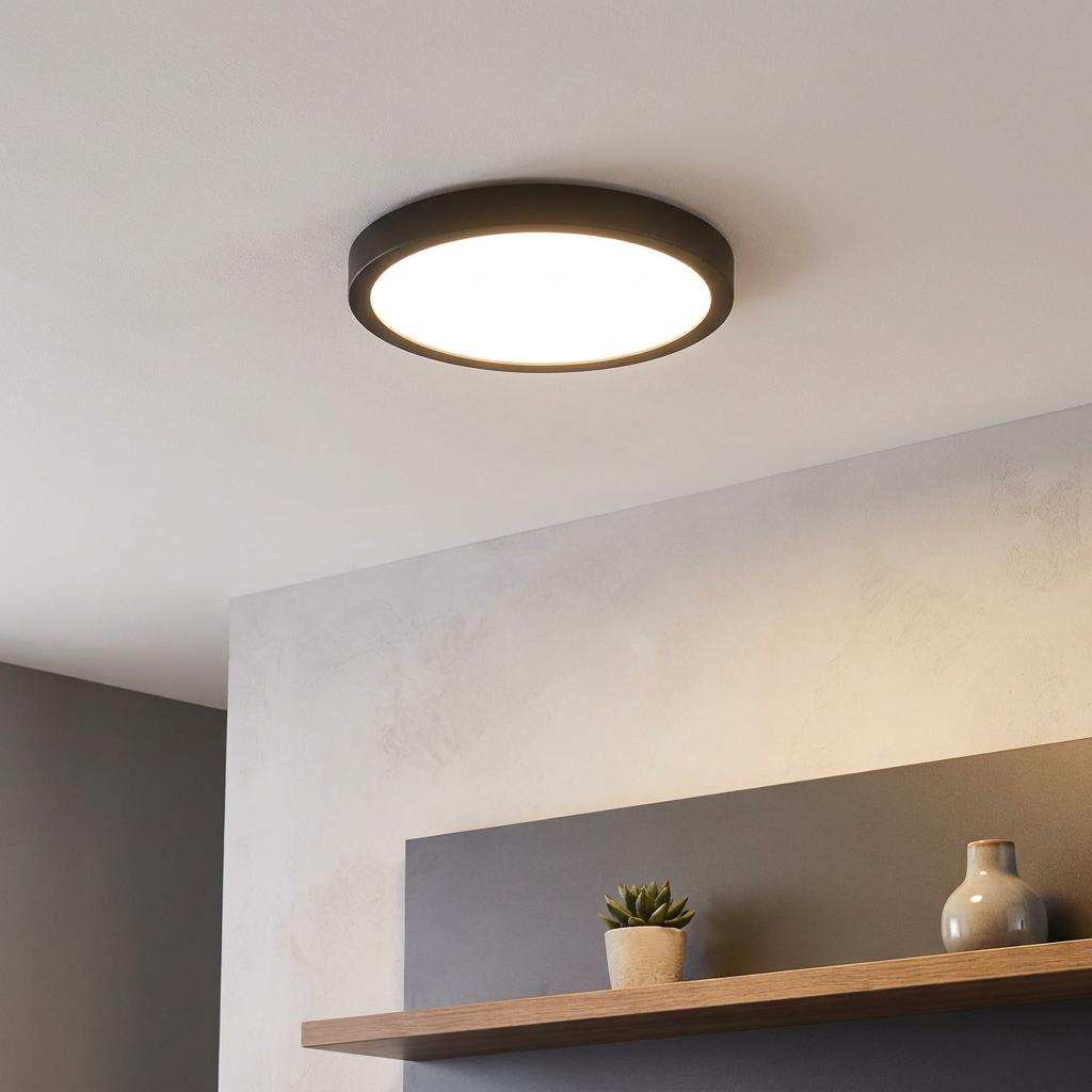 Illuminated Eglo Fueva 5 LED black round flush ceiling light mounted on a white ceiling above a minimalist shelf.