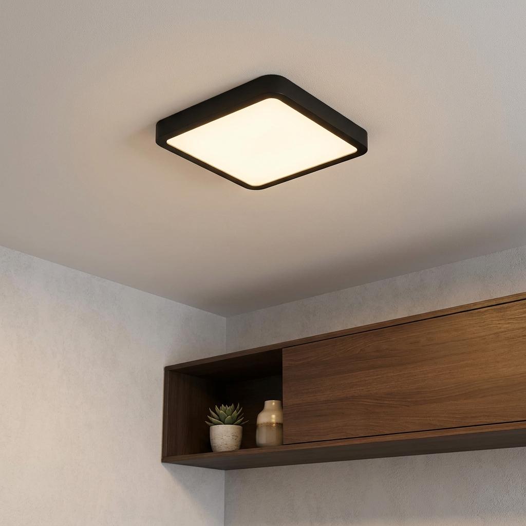 Illuminated square black flush ceiling light mounted on a white ceiling above a wooden wall shelf with decor.