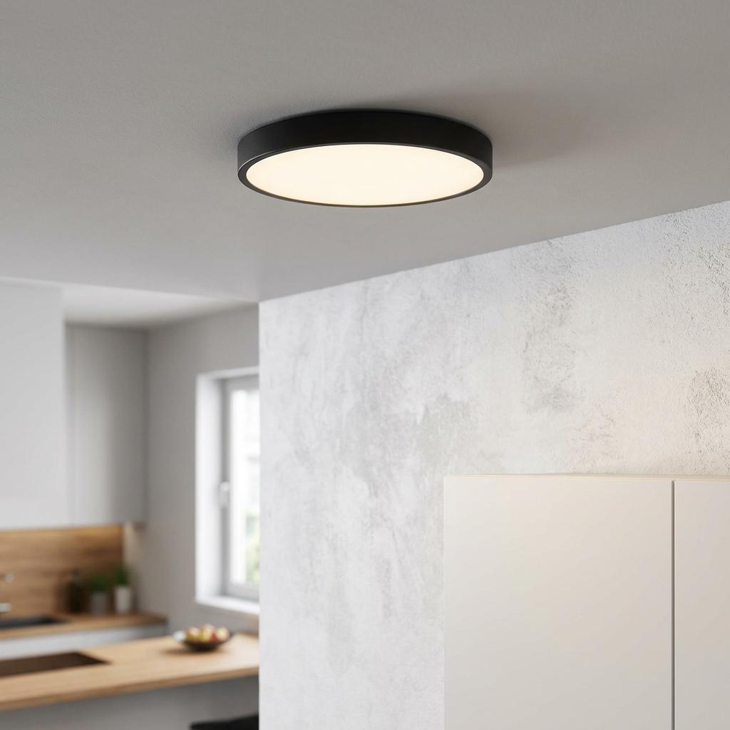 Circular black LED flush ceiling light illuminating a modern room with minimalist decor.