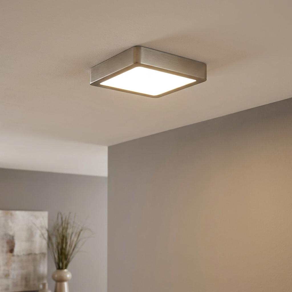 Square brushed nickel LED flush ceiling light illuminated in a modern interior.