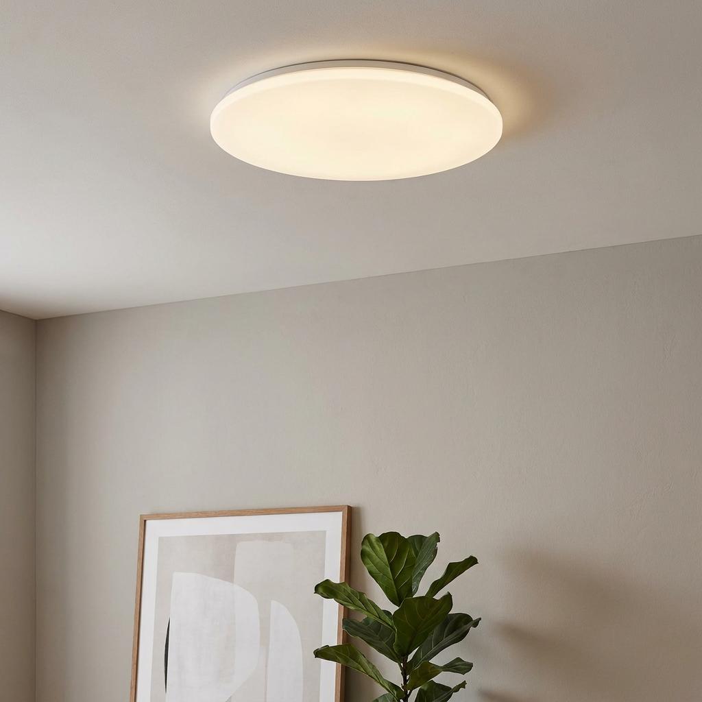 Large round Eglo Giron flush LED ceiling light glowing in a modern room with a grey wall and a plant.