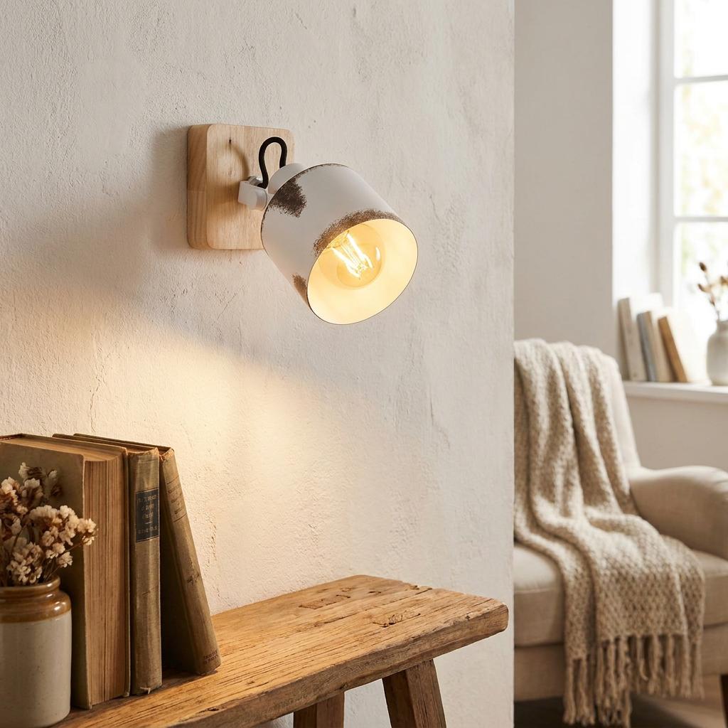 A rustic white and wood wall spotlight shines light over a wooden table with books in a cozy room.