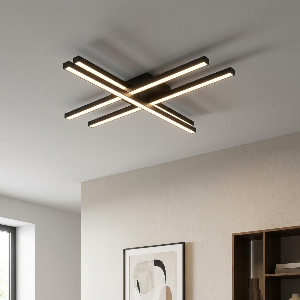 Modern black four-bar linear LED ceiling flush light glowing warm white in a minimalist room.