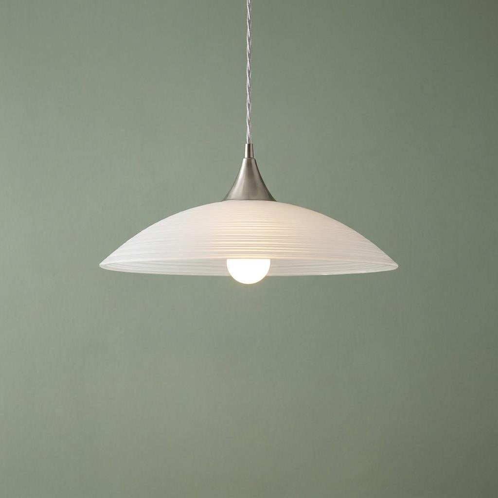 Ribbed white satin glass pendant light with brushed nickel trim hanging against a sage green wall.