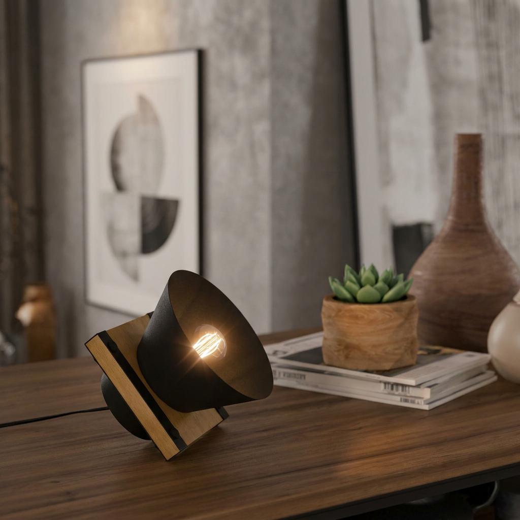 Eglo Maccles table lamp with black metal shade and wood base glowing on a desk.