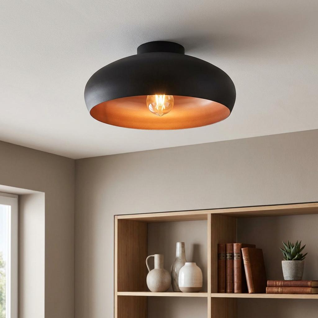 Matte black dome ceiling light with a copper interior and exposed bulb mounted in a neutral-toned room.