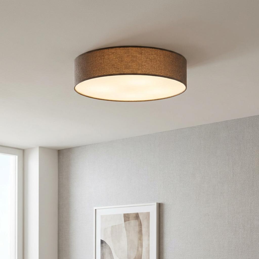 Brown linen drum shade flush mount ceiling light illuminating a modern room with a grey textured wall.