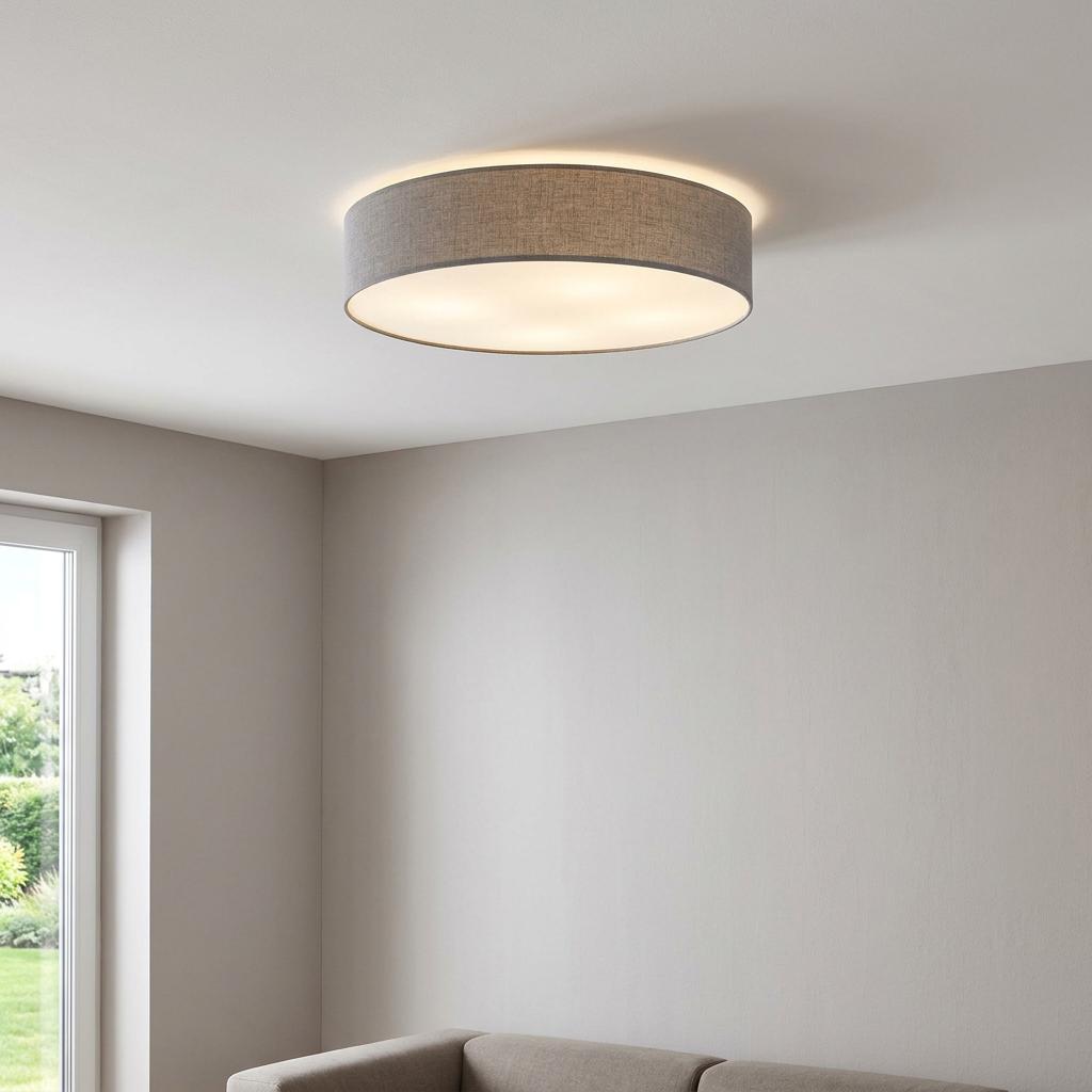 Illuminated grey fabric drum shade ceiling light in a neutral living room.