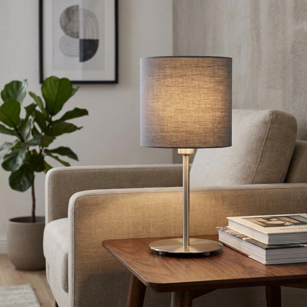 Illuminated Eglo Pasteri table lamp with a grey fabric shade and nickel base on a wooden side table.