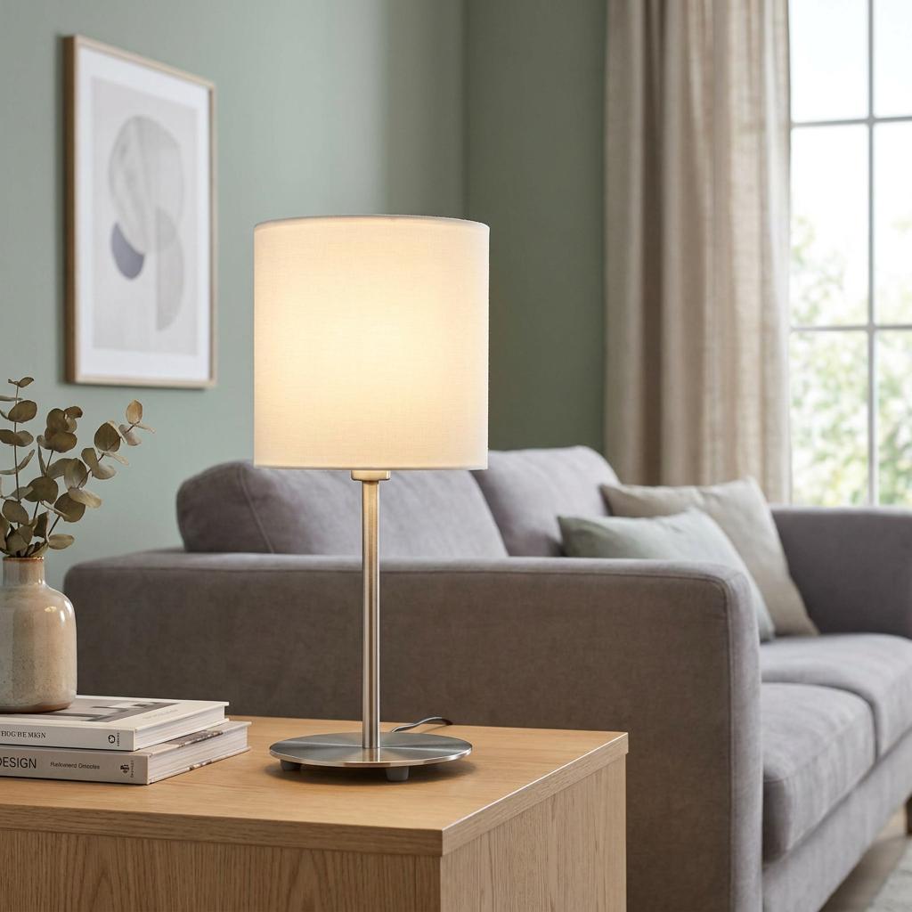 Eglo Pasteri nickel table lamp with white fabric drum shade on a wooden side table in a modern living room.