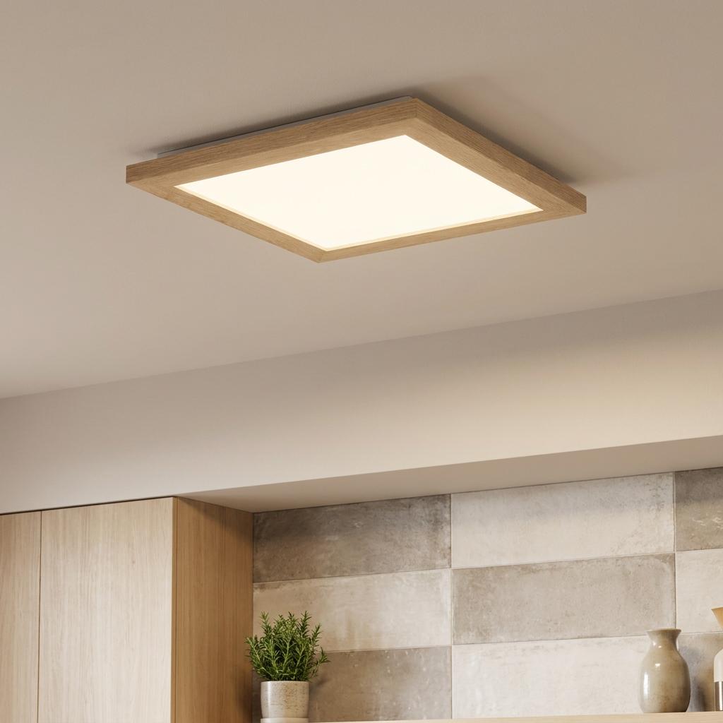 Square LED flush ceiling light with an oak wood frame glowing warmly in a modern kitchen setting.