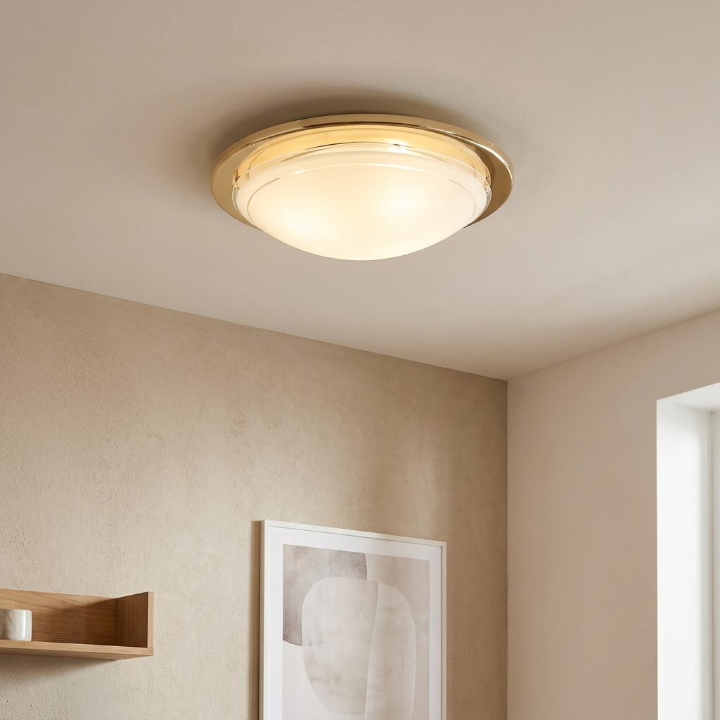 Illuminated Eglo Planet 1 brass flush ceiling light with a frosted glass shade in a minimalist interior.