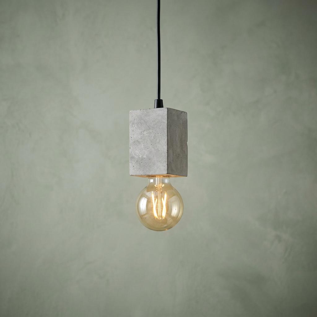 Eglo Prestwick 3 concrete block pendant light with an exposed filament bulb against a textured sage green wall.